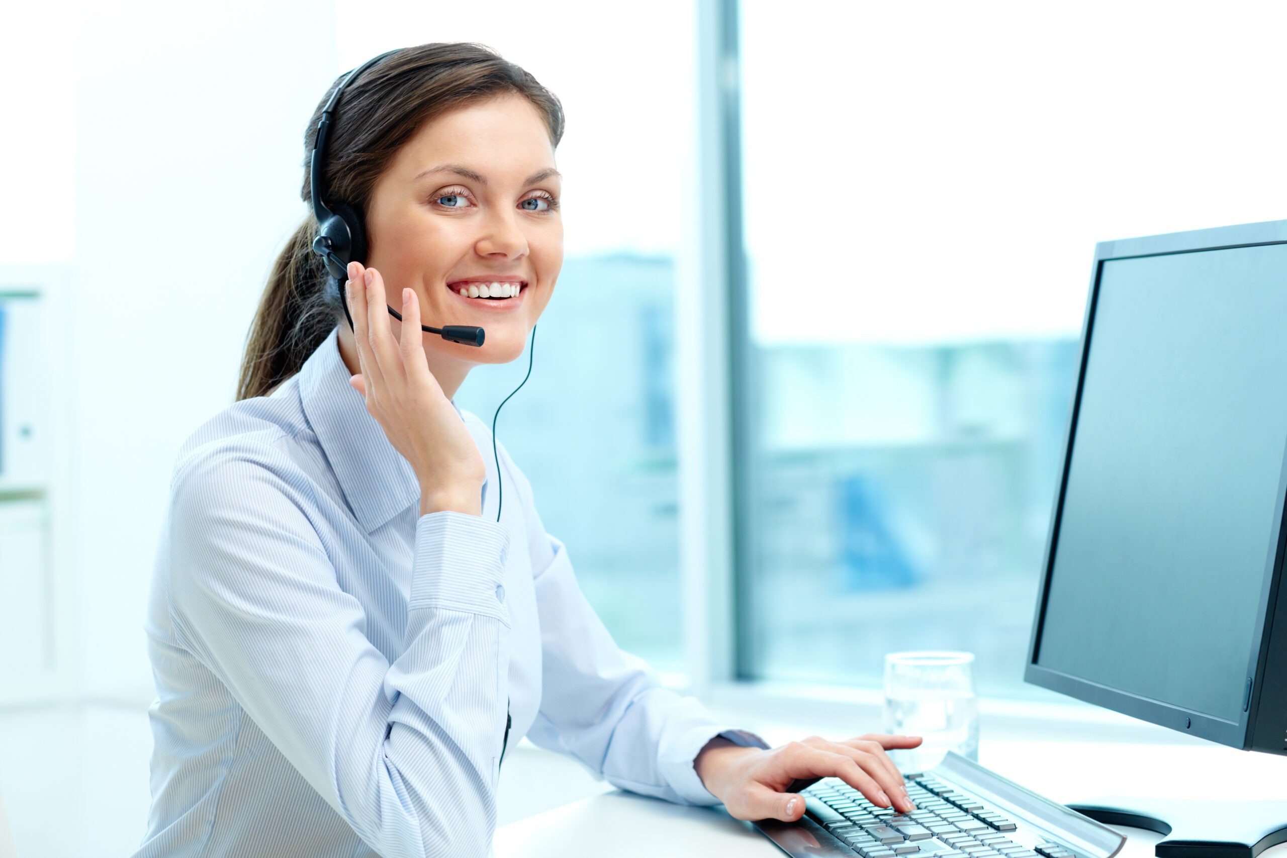 Portrait of young operator with headset looking at camera with friendly smile